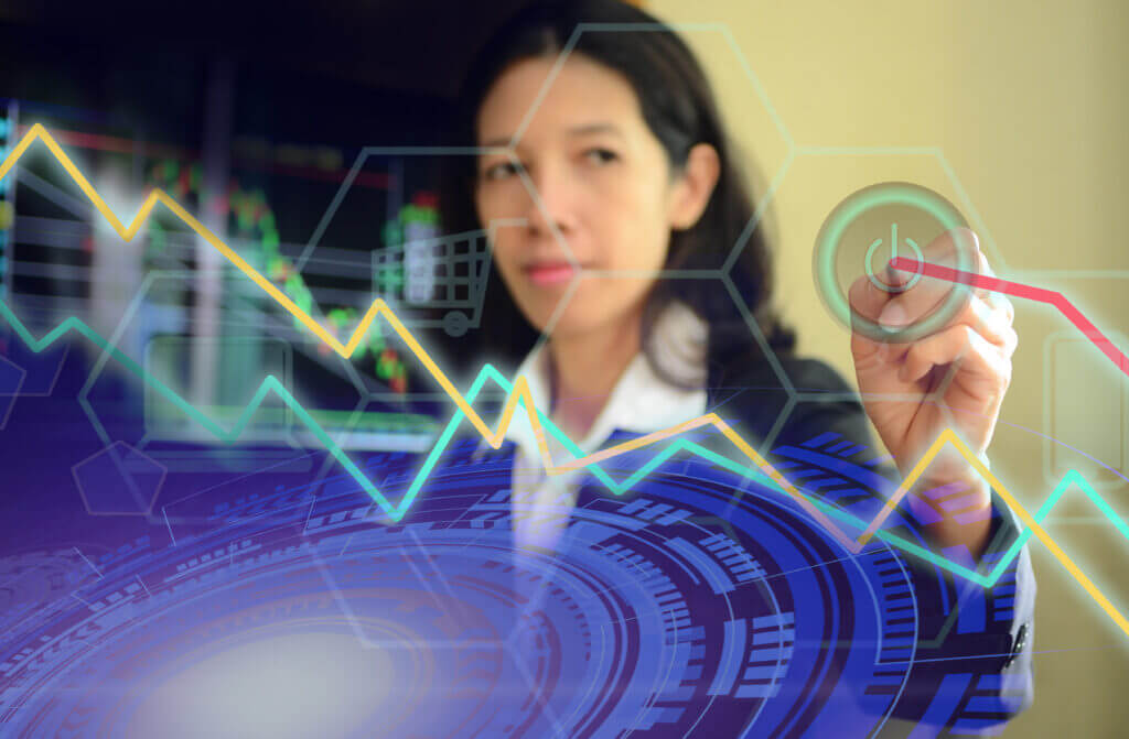 A businesswoman analyzes financial data, drawing graphs on a digital interface. Background displays stock market trends with colorful lines representing data fluctuations, indicating a focus on analytics and investment strategy.